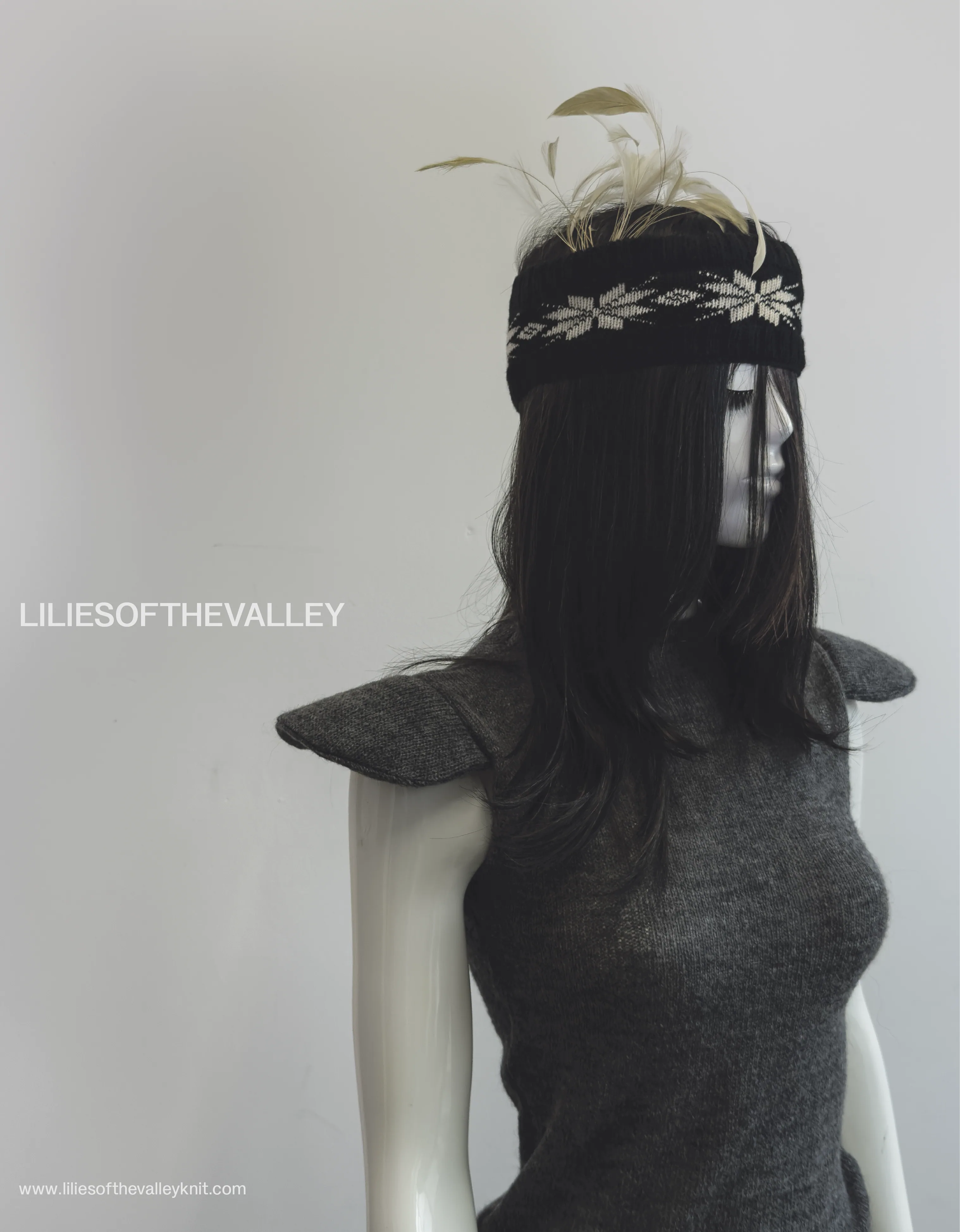 Lilies of the Valley campaign image for Toe Rag: a mannequin in a grey
                    knitted top with peaked shoulders, wearing a black and cream Fair Isle
                    headband trimmed with feathers.