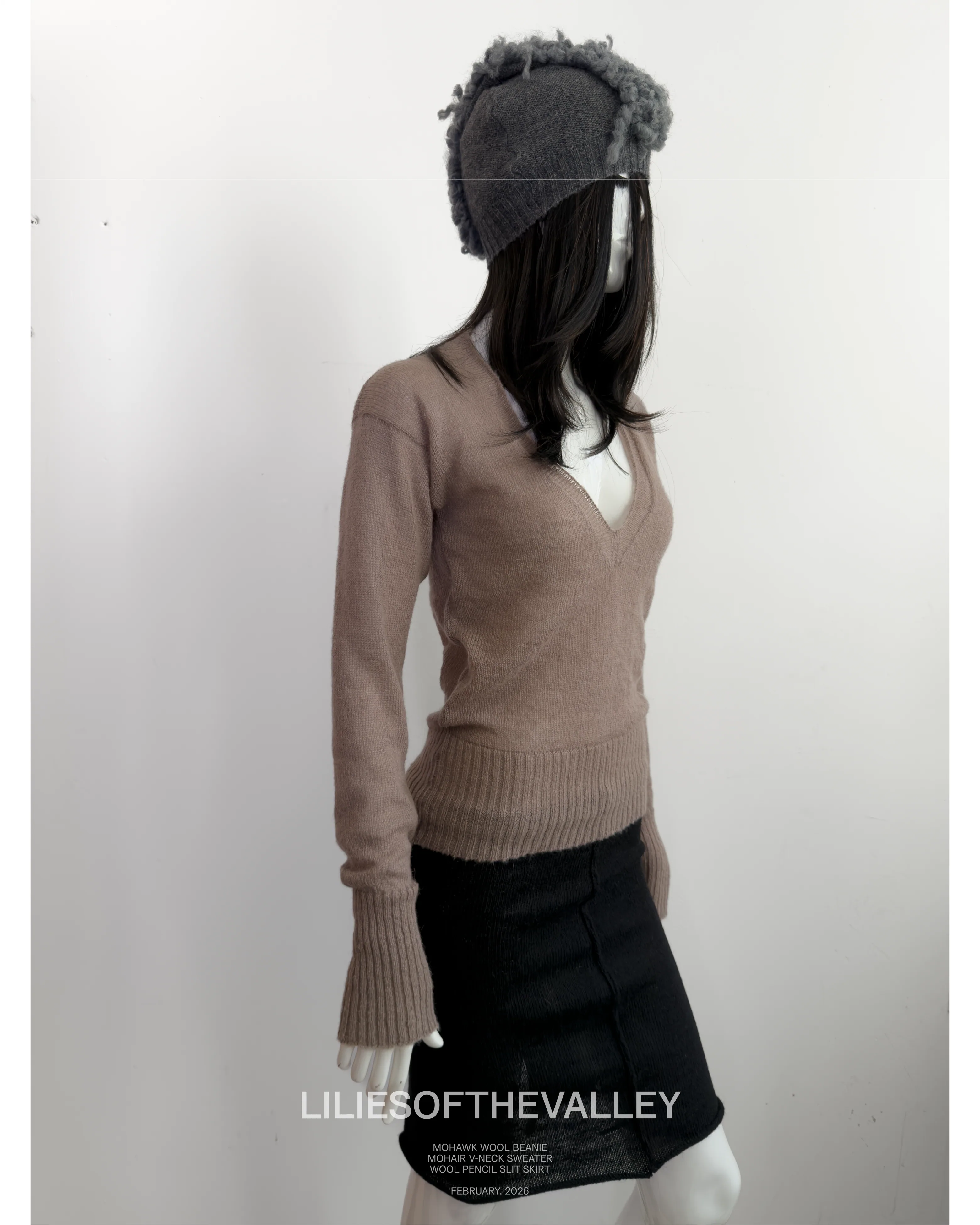 Campaign frame: a camel V-neck over a black skirt, with a grey knitted
                    cap.